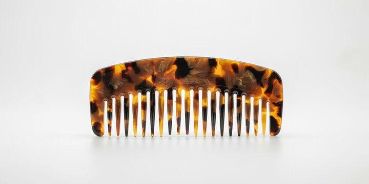 Tortoiseshell pattern hair comb with fine teeth isolated on a plain white background, for hair care, and grooming styling accessories