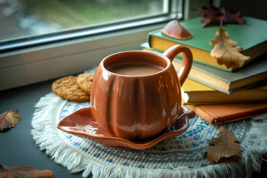 Autumn vibes. Mug of hot chocolate or cocoa, cookies and books near window. Warm cozy fall mood. 