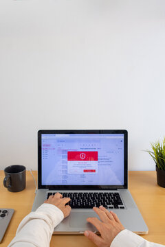 Hands using laptop with email security alert on screen