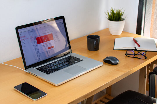 Laptop showing email security alert beside smartphone on office desk