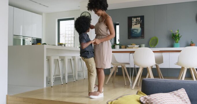 Mother, child and holding hands in home for dancing, learning steps and guidance for care. Playful family, African woman and boy in living room for fun, bonding and balance on feet with rhythm