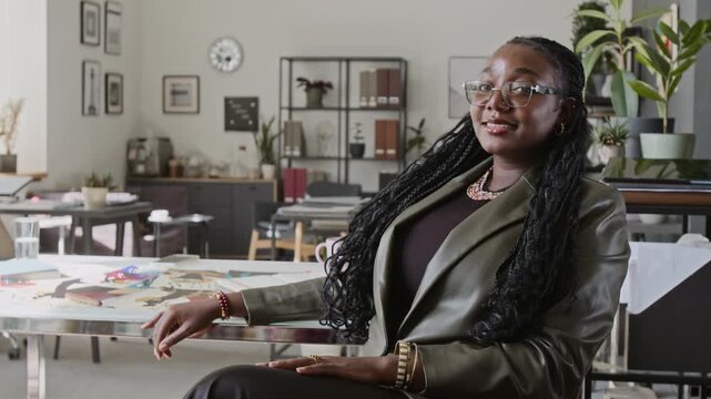 Portrait of young adult African American businesswoman turning head, looking into camera in design studio. Clip fits corporate leadership campaigns, employment ads, diversity marketing projects