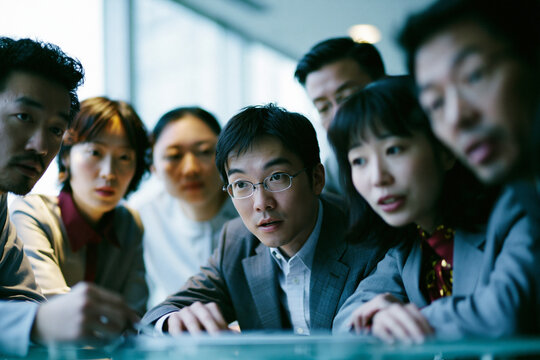 Asian Business Team Collaborating Closely in Office Meeting