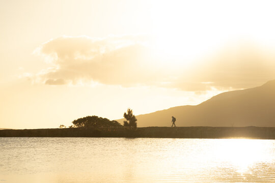 lone silhouette hiker at sunset walking nature path near water and mountains, Stanford, South Africa