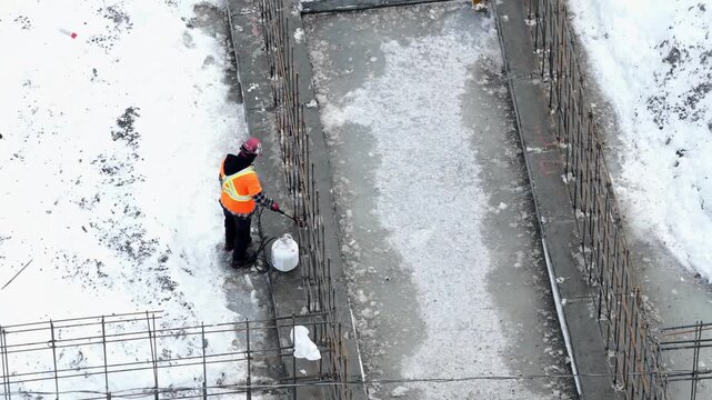 Worker Using Propane Torch to Melt Ice on Rebar at Construction Site