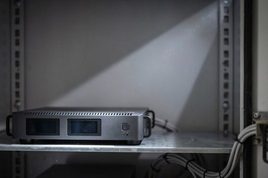 Compact edge server on a steel shelf inside a roadside cabinet lit by a torch