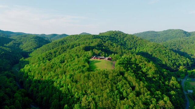 Great Smoky Mountains aerial drone view over a forested ridge near Hartford, Tennessee, with a secluded hilltop house and green lawn in a clearing among thick woods.