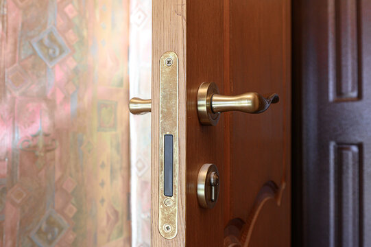 Wooden interior door with brass lever handle, vertical deadbolt, keyed cylinder lock, patterned glass panel, warm wood grain, geometric tile accents, classic hardware