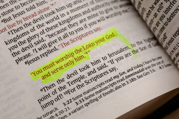Obraz premium Close up view of an open holy book with scripture text highlighted in bright yellow marker, showcasing devotion, study, and spiritual focus