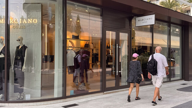 15.09.2026,Porto Montenegro.Storefront of the Marciano by Guess boutique in Porto Montenegro, Tivat, featuring mannequins and two passersby on the pedestrian street.