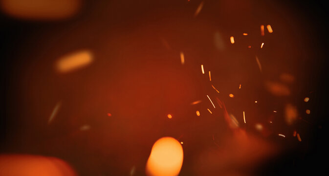 Fire embers particles over black background. Fire sparks background. Abstract dark glitter fire particles lights.