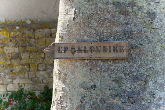 Tree trunk with CP Klondike wooden direction sign at French village of Sainte-Marie-du-Mont on a summer day. Photo taken July 16th, 2026, Utah Beach, Sainte-M&egrave;re-&Eacute;glise, Normandie, France.