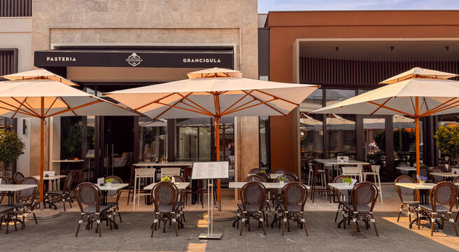 15.09.2026,Porto Montenegro.Grancigula Pasteria restaurant terrace in Porto Montenegro, Tivat, with outdoor tables, cafe chairs and large white umbrellas in a modern pedestrian setting.