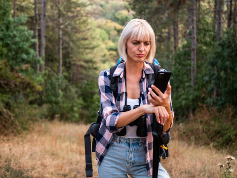 Worried woman hiker got lost and she is using smartphone to find right direction while hiking in the nature.