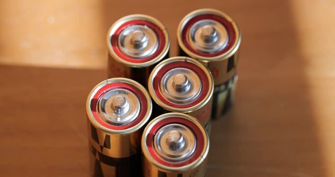 Top down close up view of small alkaline C size power batteries arranged on a wooden table surface under warm light
