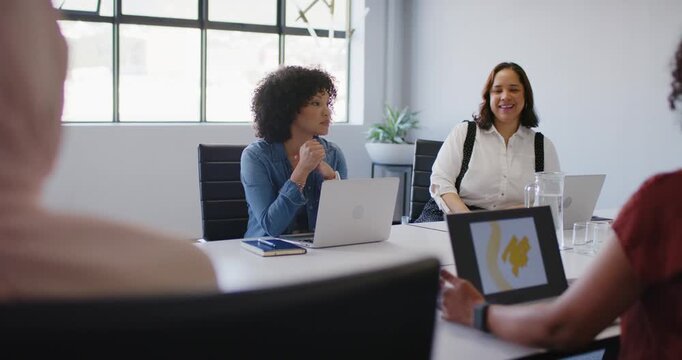 African American women reacting as rust top presenter showing yellow slide on laptop pitching idea
