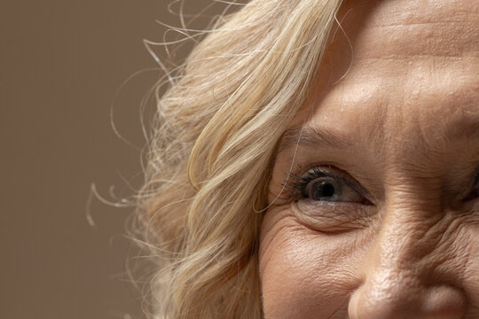 Senior female smiling, showing right half of face in studio, highlighting eye, eyeliner, eyelashes