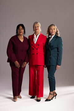Senior and mature adult women posing in studio with burgundy red teal suits white blouses heels