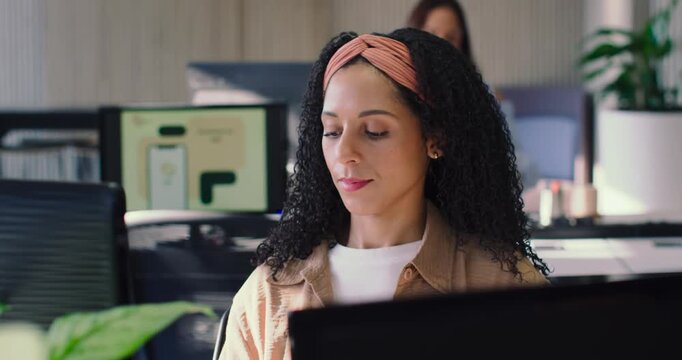 African American women working in open office, main woman in tan jacket answering phone and smiling
