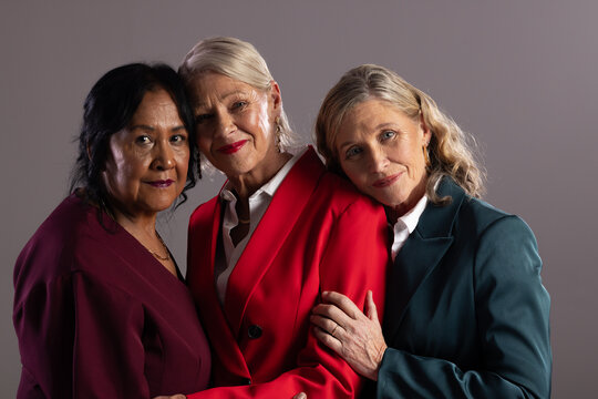 Diverse female friends posing together in studio portrait wearing tailored blazers and white shirt
