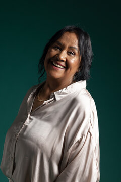 Senior African American woman smiling, posing in studio wearing satin blouse and gold necklace