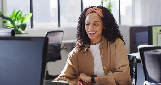 African American woman in tan top tapping tablet, typing at office after seeing happy note