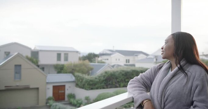 African American woman in robe leaning on rail balcony, camera nearing causing smile, copy space