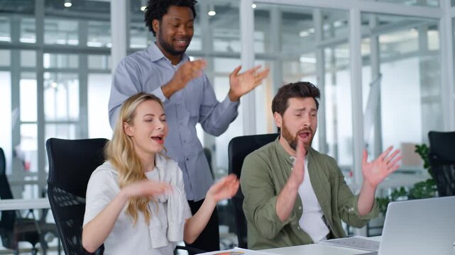 Active happy multiethnic business team dancing repeating same movement with hands singing celebrating teamwork dance listening music together fun clapping palm three multiracial partners in office