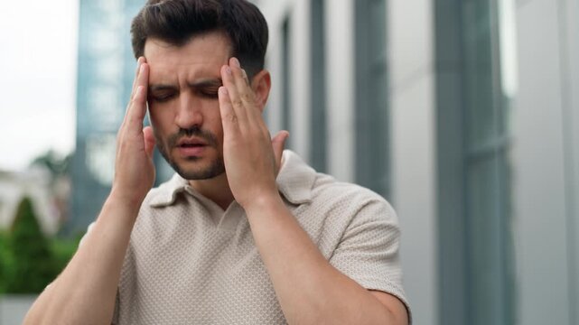Close up frustrated young Caucasian business man feeling headache dizzy head pain fatigued depressed male businessman guy feel migraine blood tension pressure health problem mental disorder in city