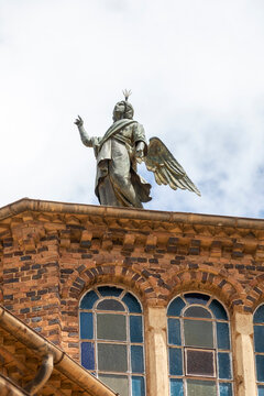 A weathered angel statue stands atop the ornate brick rooftop of a colonial-era building, Central Region, Asmara, Eritrea