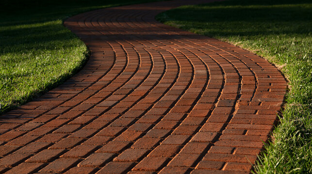 Elegant photo of A winding red brick path meanders through a lush green garden lawn. Represents a tranquil walking trail or landscape design concept.