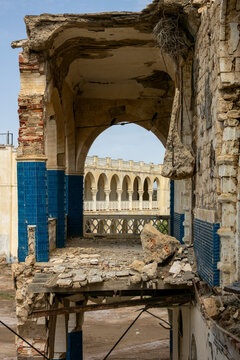 A broken archway with blue tiled walls frames a colonnaded balcony inside the ruined old palace of Haile Selassie, Northern Red Sea, Massawa, Eritrea