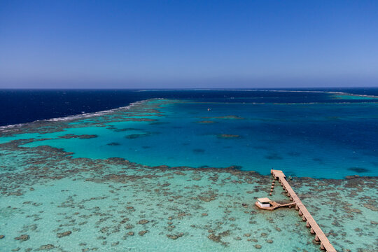 Aerial view of the turquoise lagoon enclosed by Sanganeb reef with a small pier and building, Red Sea State, Sanganeb, Sudan