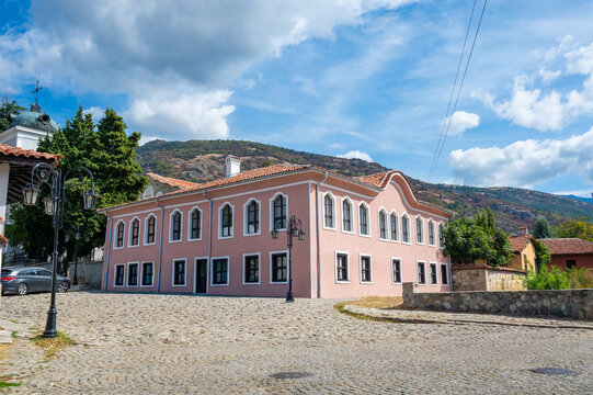 Exterior view of a historic Bulgarian National Revival girls school building with mountain landscape
