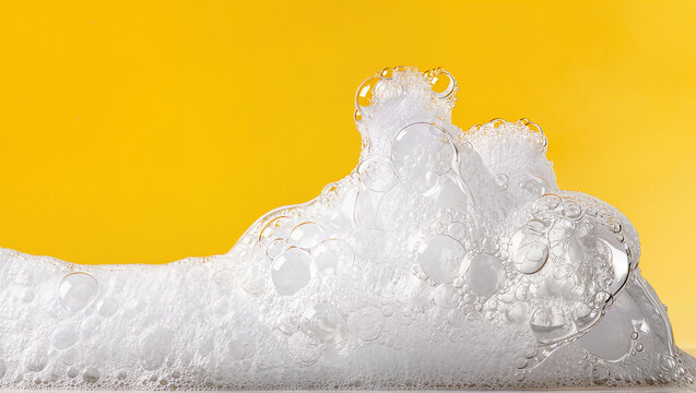 White soap foam and bubbles against bright yellow background, cleaning suds and fresh hygiene concept with copy space for text