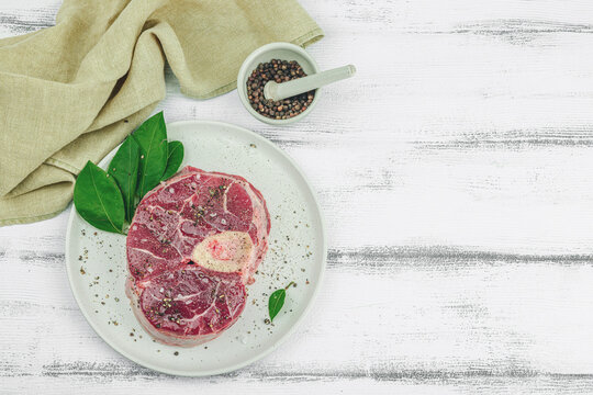 Raw ossobuco beef meat with spices and fresh herbs. Veal shank steak, traditional Italian ingredient