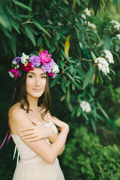 Close up portrait of a beautiful young girl with flower wreath in a sunny garden