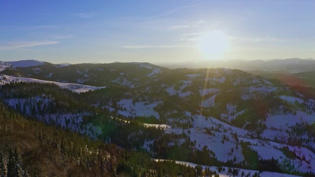 High snowy mountain covered with evergreen fir trees on a sunny cold day