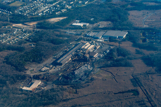 Aerial view of an industrial area near the Raritan River in central New Jersey, showing rail sidings, material stockpiles, and processing buildings
