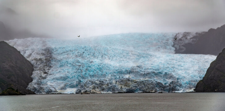 Tour boat beneath the massive Holgate Glacier in Kenai Fjords National Park, Alaska