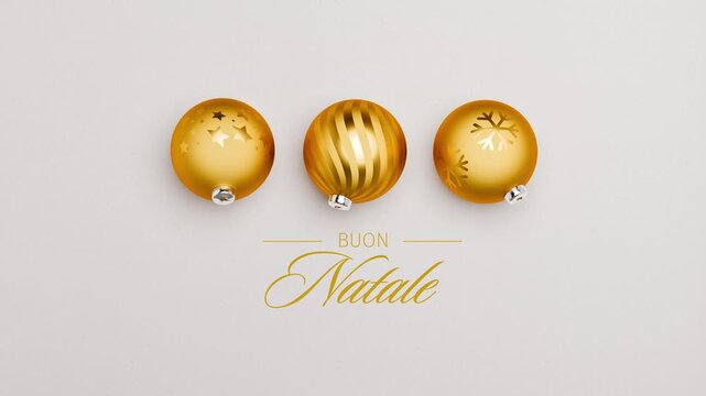 Three golden christmas baubles spinning on a paper surface. Italian language Merry Christmas messages (Buon Natale) appearing and dissolving. Loopable video