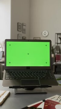 Vertical shot of laptop with green screen chroma key display and tracking markers standing on office desk. Footage ideal for software mockup, UI design preview or website presentation