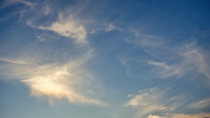 Obraz premium Beautiful Golden Sun Glow Illuminating Wispy Cirrus Clouds Against a Deep Blue Sky During Sunset or Sunrise, Perfect for Nature Backgrounds, Atmospheric Weather, and Calm High Altitude Scenery