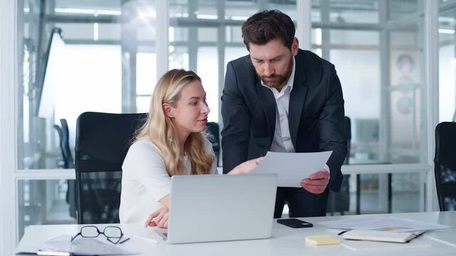 Two business colleagues Caucasian businesswoman talking with businessman showing document in office woman explain corporate instruction to man in company male asking female boss help with paperwork
