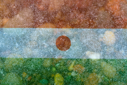 The national flag of Niger, projected in close‑up onto river ice with a scattering of colorful stones.