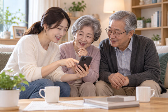 Korean woman helping senior parents learn to use a smartphone at home