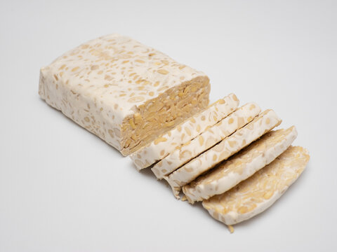 Sliced tempeh or tempe, a traditional Indonesian food made from whole soybeans that are fermented and pressed into a dense, firm cake, isolated in a white background
