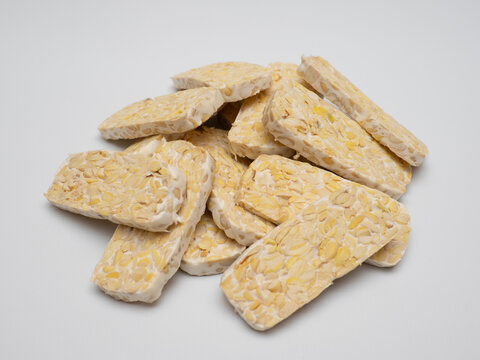 Sliced tempeh or tempe, a traditional Indonesian food made from whole soybeans that are fermented and pressed into a dense, firm cake, isolated in a white background