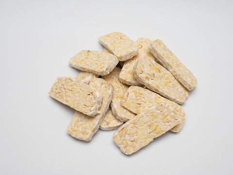 Sliced tempeh or tempe, a traditional Indonesian food made from whole soybeans that are fermented and pressed into a dense, firm cake, isolated in a white background
