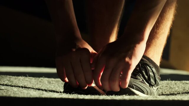 Man touches shoes with hands stretching body in sports club. Motivated sportsman improves flexibility with basic exercises
